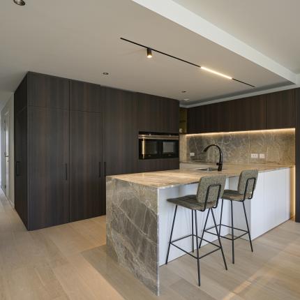 Leefkeuken in natuursteen met warme accenten en toegang tot de berging via de kastenwand - deel 01